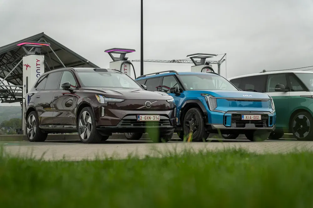 Volvo et Kia électriques en charge, station moderne à l'horizon.