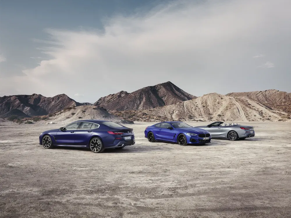 Drie BMW's in blauw en zilver, geparkeerd in een bergachtige woestijn.