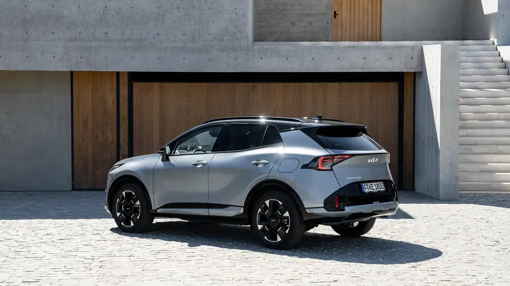 Kia Sportage 2023 gris argenté devant une maison moderne en béton et bois.