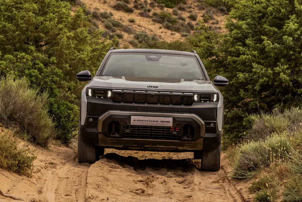 {"fr":"Jeep Compass 4xe sur terrain sablonneux entouré de végétation boisée.","nl":"Jeep Compass 4xe op zanderig terrein omringd door bosrijke vegetatie."}