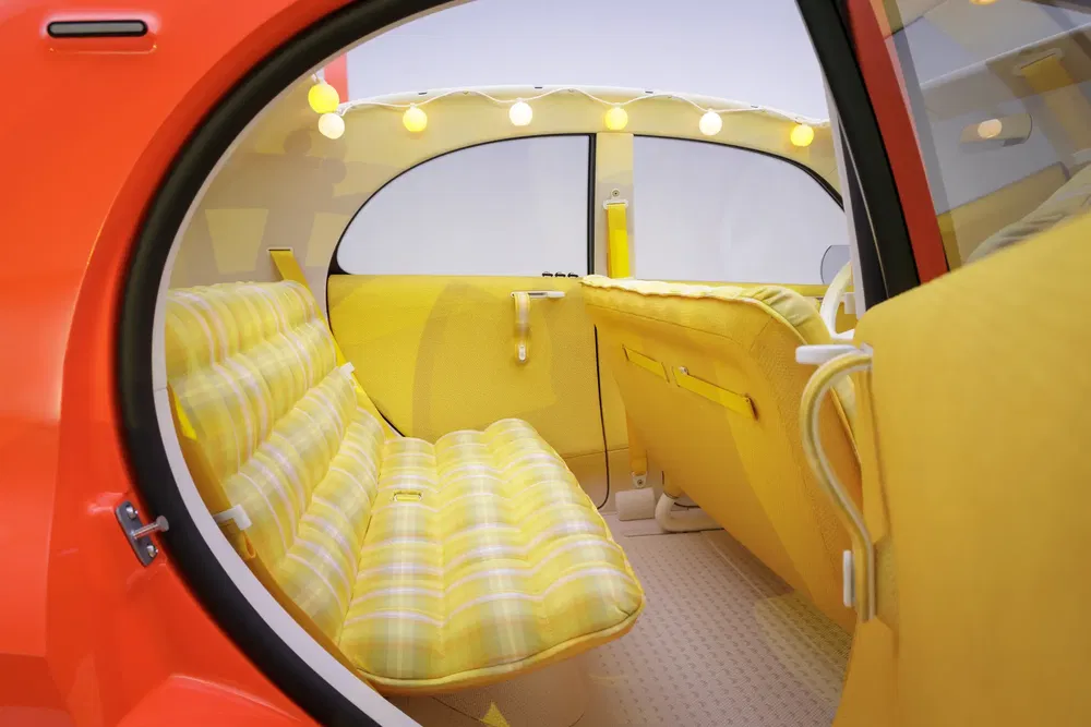 Intérieur rétro d'une voiture concept avec banquettes jaunes et lumières à ampoules rondes.