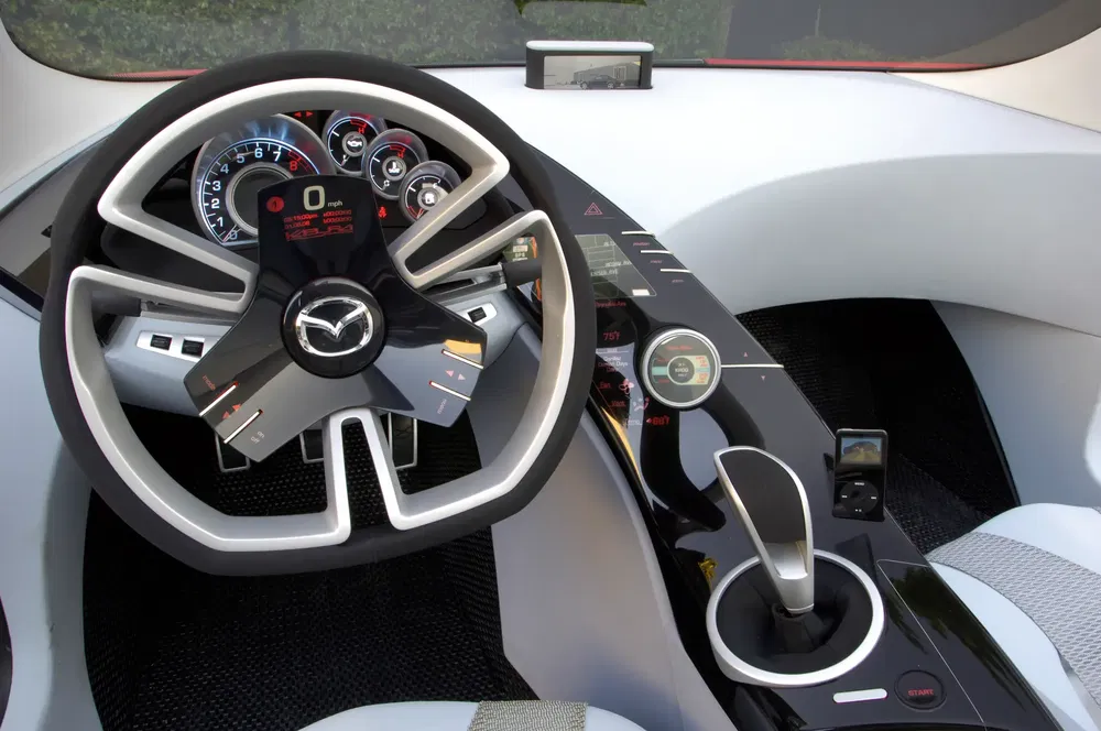 Intérieur futuriste de voiture Mazda avec volant unique et tableau de bord numérique.