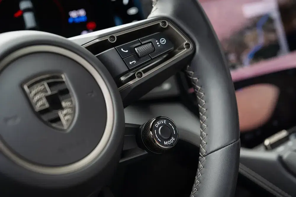 Volant Porsche avec commande Drive Mode et boutons multifonction, intérieur moderne et élégant.