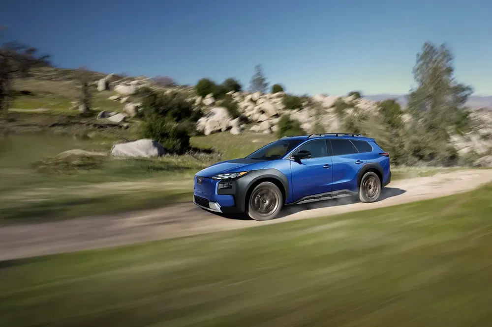 Hyundai Santa Fe bleu 2024 roulant sur un chemin rural entouré de verdure.