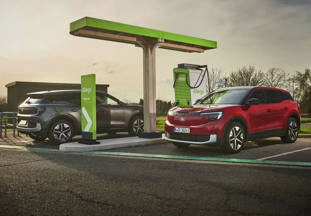 Twee elektrische Ford-auto's bij een Allego-laadstation onder een bewolkte lucht.