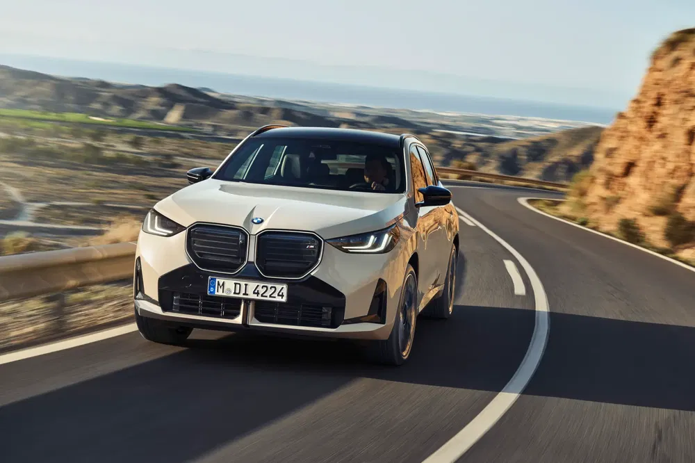 BMW X3 M en conduite dynamique sur une route de montagne sinueuse.
