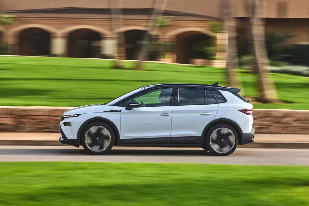 Hyundai Kona électrique blanche roulant sur une route bordée de verdure luxuriante.