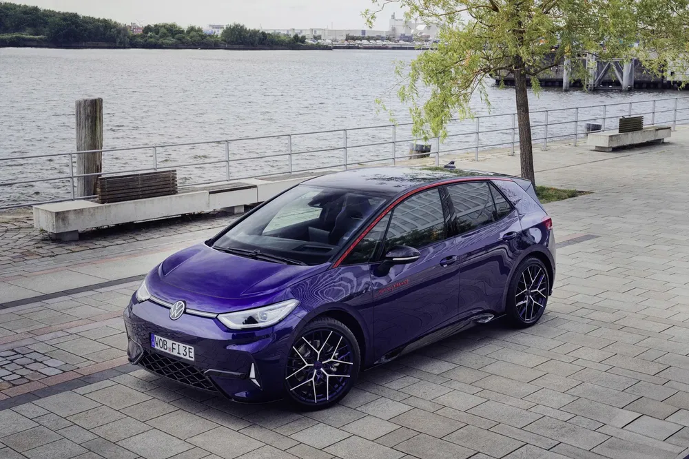 Paarse Volkswagen ID.3 geparkeerd bij water, moderne styling en zwarte sportwielen.