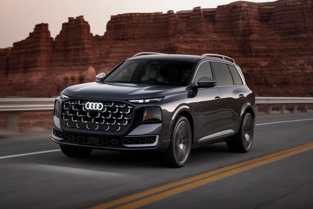 Audi SUV rijdt op een schilderachtige weg met rotsformaties op de achtergrond.