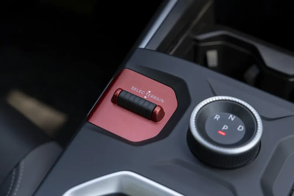 Sélecteur de terrain et commande de vitesse sur console centrale de véhicule moderne.