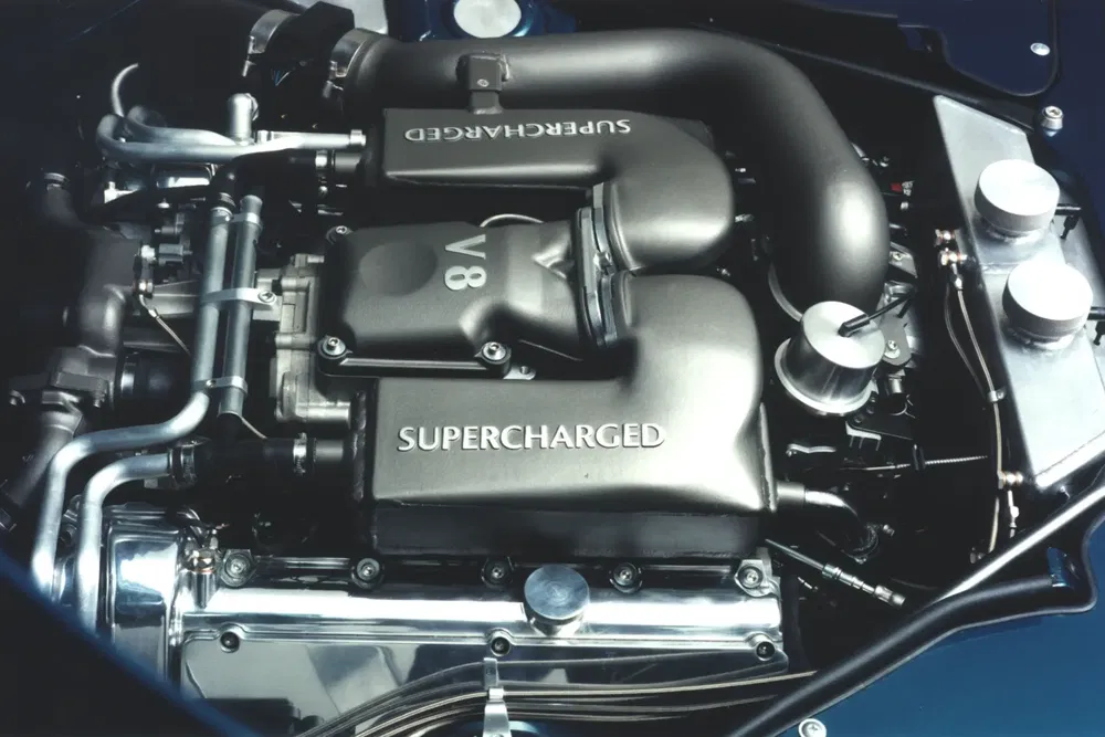 Moteur V8 suralimenté Jaguar, composants métalliques visibles, design haute performance.