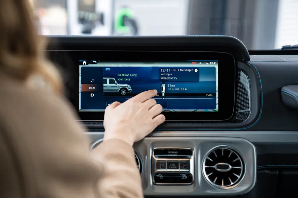 Main interagissant avec l'écran tactile du système d'infodivertissement d'une Mercedes G-Class.