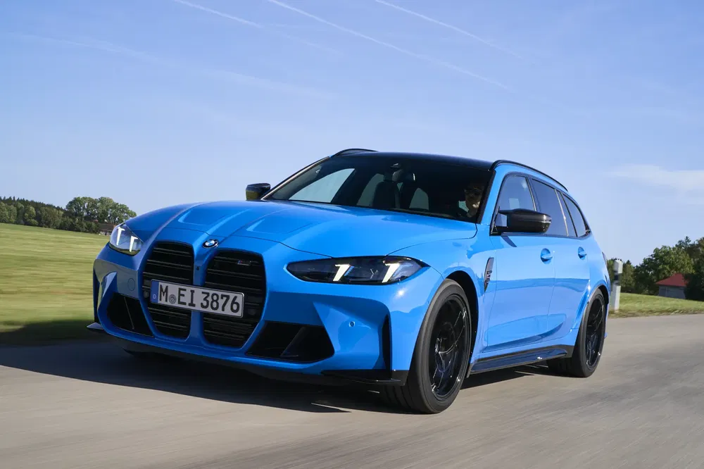 Blauwe BMW rijdend op weg, heldere lucht, dynamisch ontwerp, sportieve prestaties.