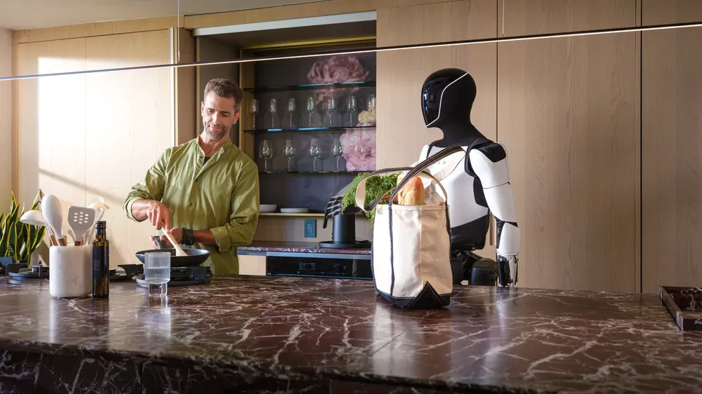 Un robot humanoïde assiste un homme cuisinant dans une cuisine moderne.