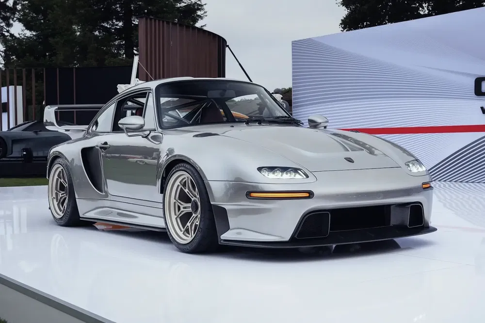Moderne zilveren Porsche auto met sportvelgen en achterspoiler, op een tentoonstellingsplatform.