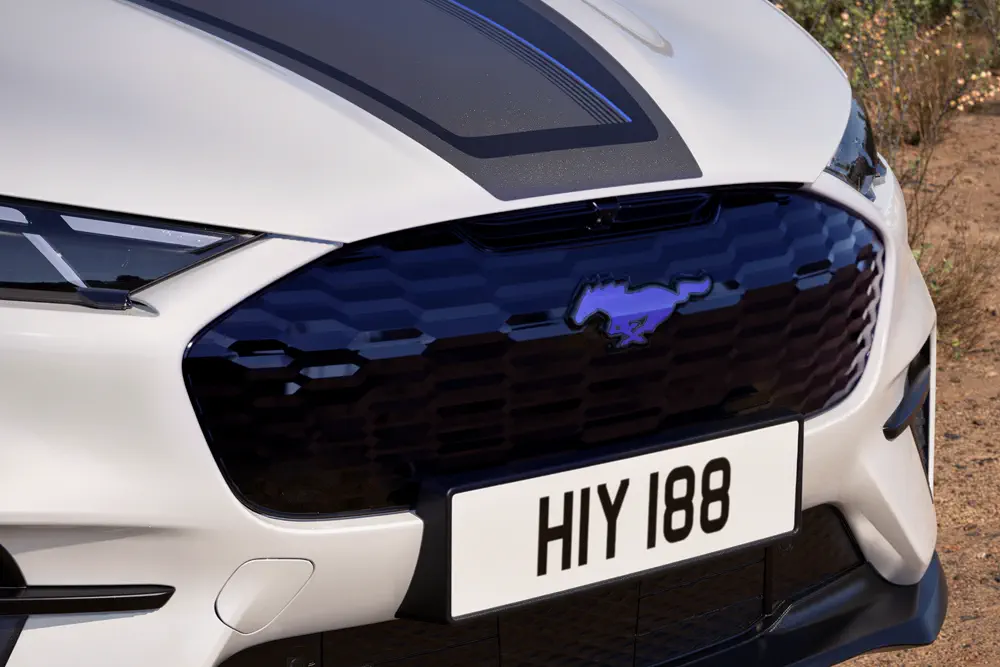 Calandre sportive Ford Mustang blanche sur route désertique, plaque d'immatriculation HIY 188.