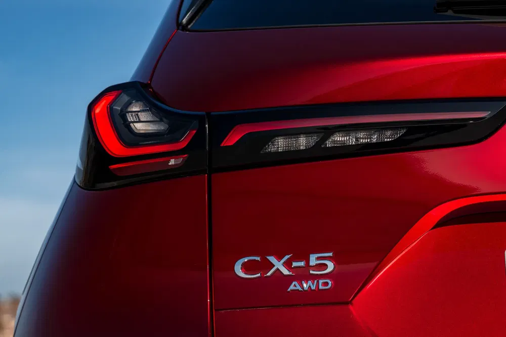 Achterlicht van een rode Mazda CX-5 AWD onder heldere hemel.