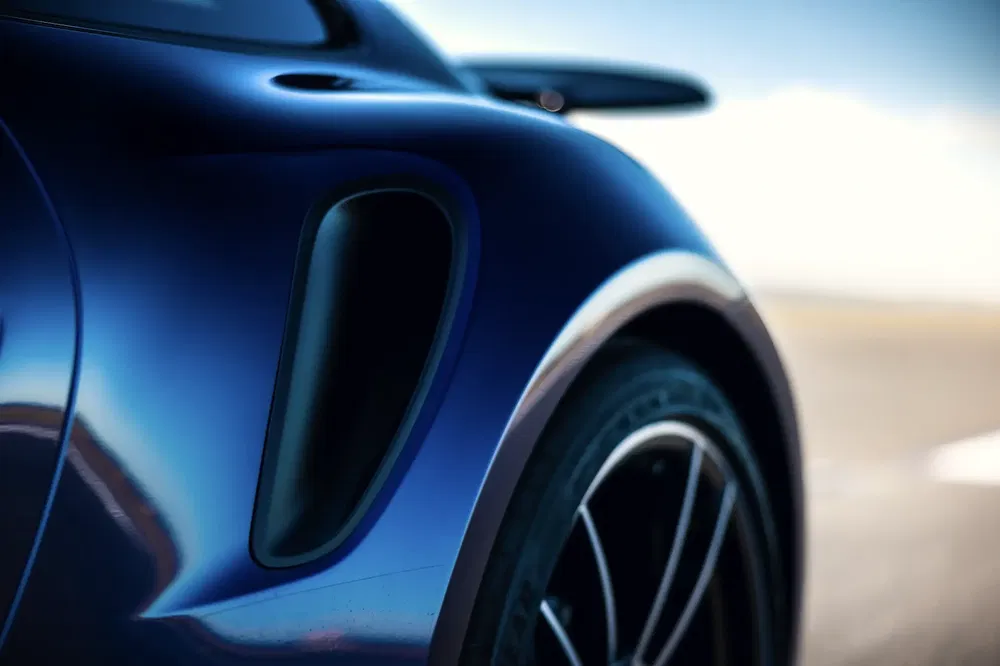 Detail van een luchtinlaat op een blauwe Porsche, benadrukt sportieve aerodynamica.