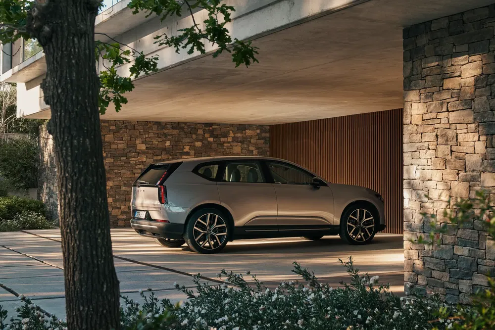 SUV moderne garé sous un abri, design élégant et luxueux, maison en pierre.