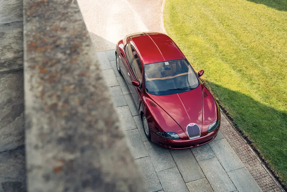Voiture Bugatti EB112 rouge garée, vue de dessus, sur fond de pelouse verte.