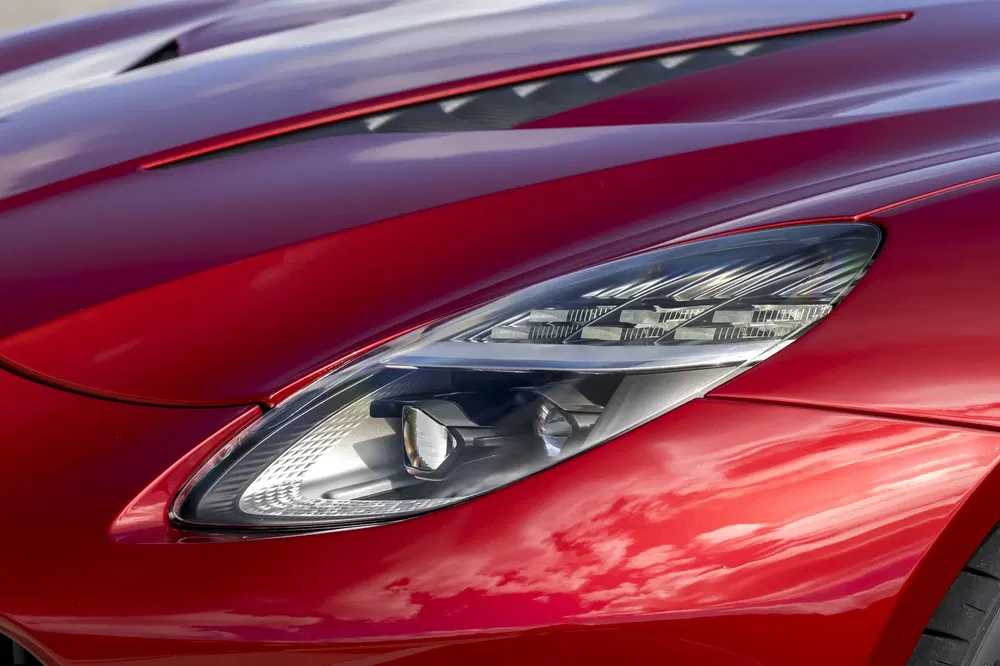 Phare avant d'une voiture de sport rouge avec finitions aérodynamiques modernes.