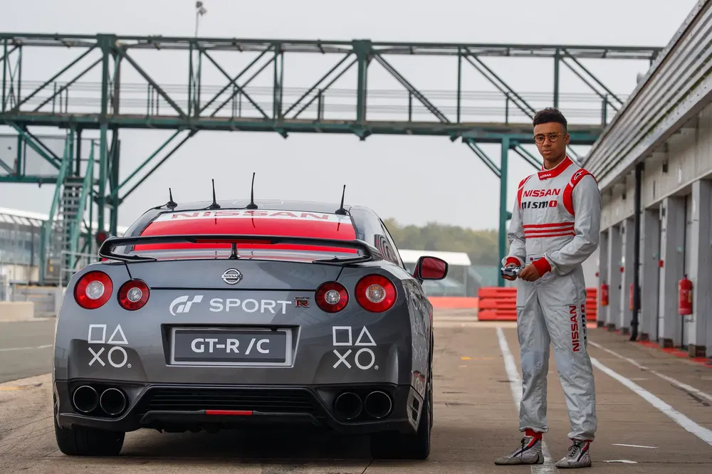 Nissan GT-R sur piste avec pilote en combinaison de course Nismo, préparation pour la course.