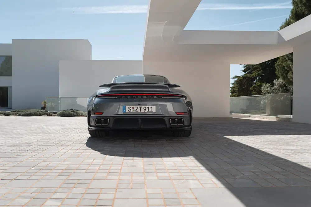 Vue arrière de la Porsche 911 Turbo S, stationnée devant une maison moderne minimaliste.