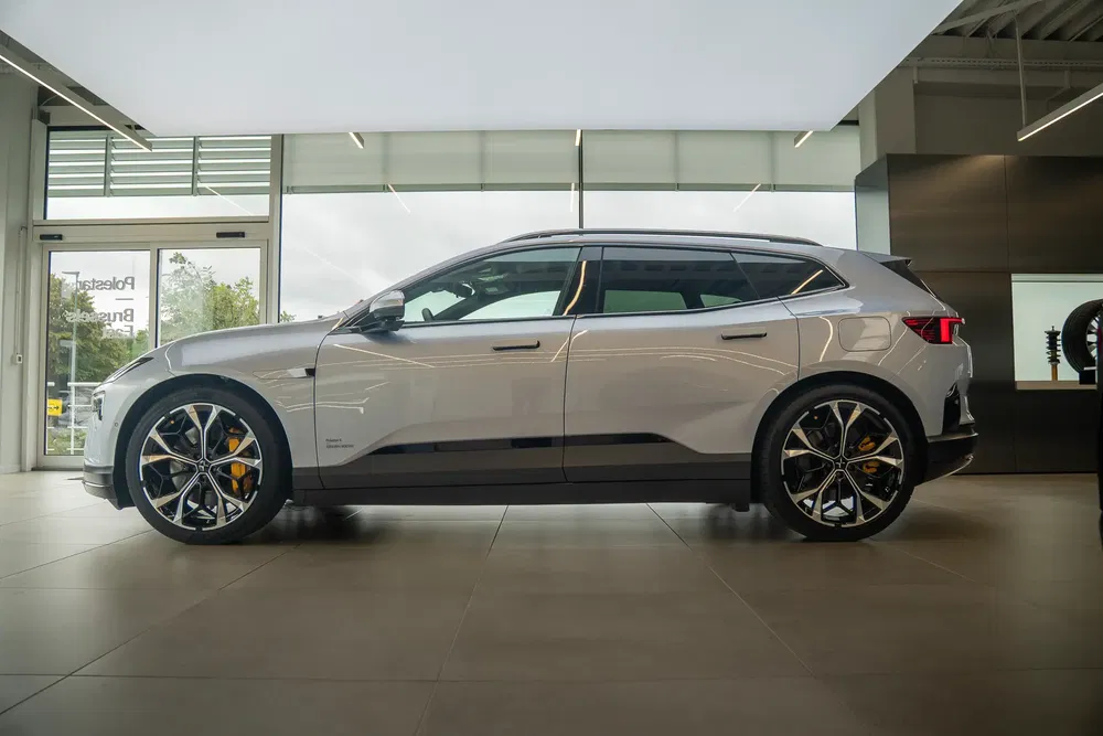 Voiture Polestar 2 grise vue latérale dans un showroom moderne.