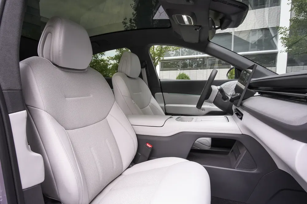 Intérieur moderne et spacieux d'une voiture électrique avec sièges en cuir blanc.