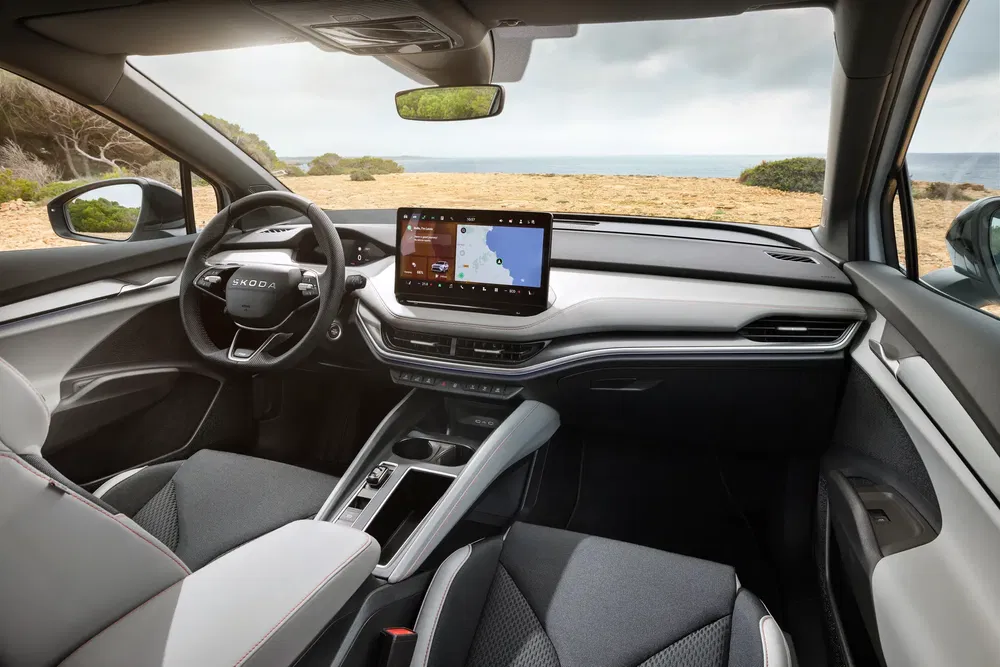 Intérieur moderne et spacieux du Skoda Enyaq avec écran tactile et vue sur mer.