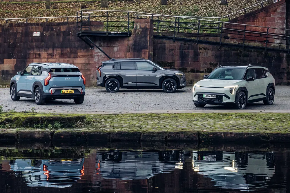 Drie Kia Niro 2023 auto's geparkeerd bij een kade, rustige herfstachtige sfeer.