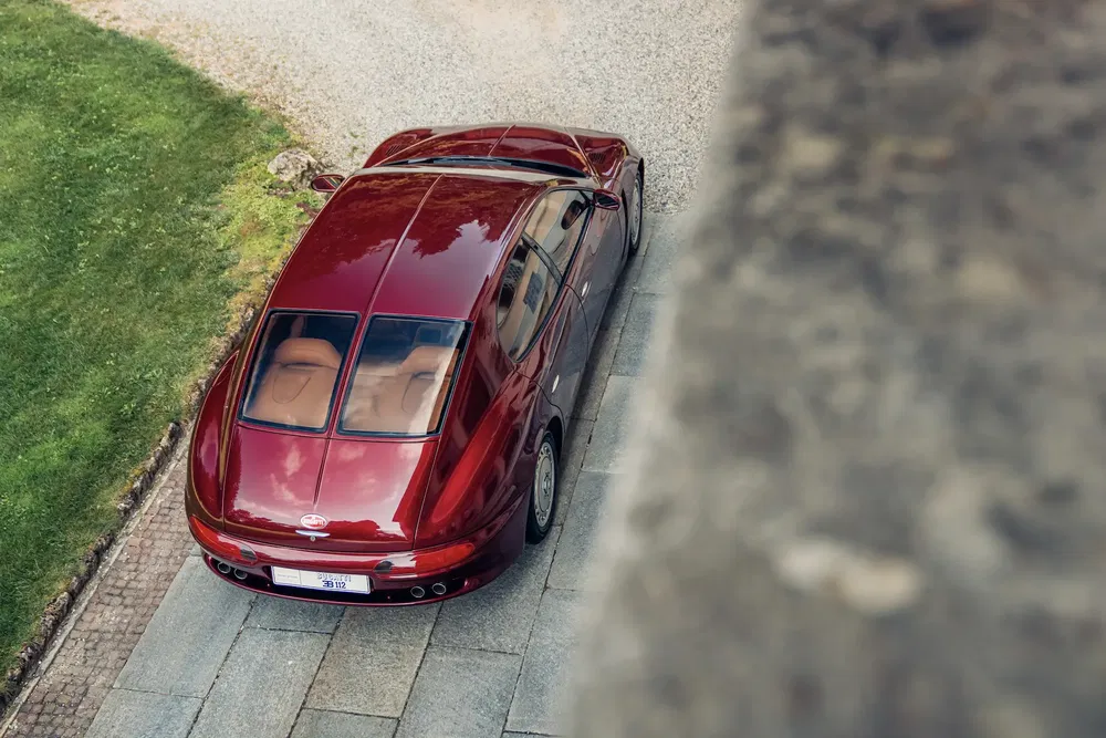 Voiture rouge sport Maserati Quattroporte vue de dessus, allée pavée, arrière-plan herbe.