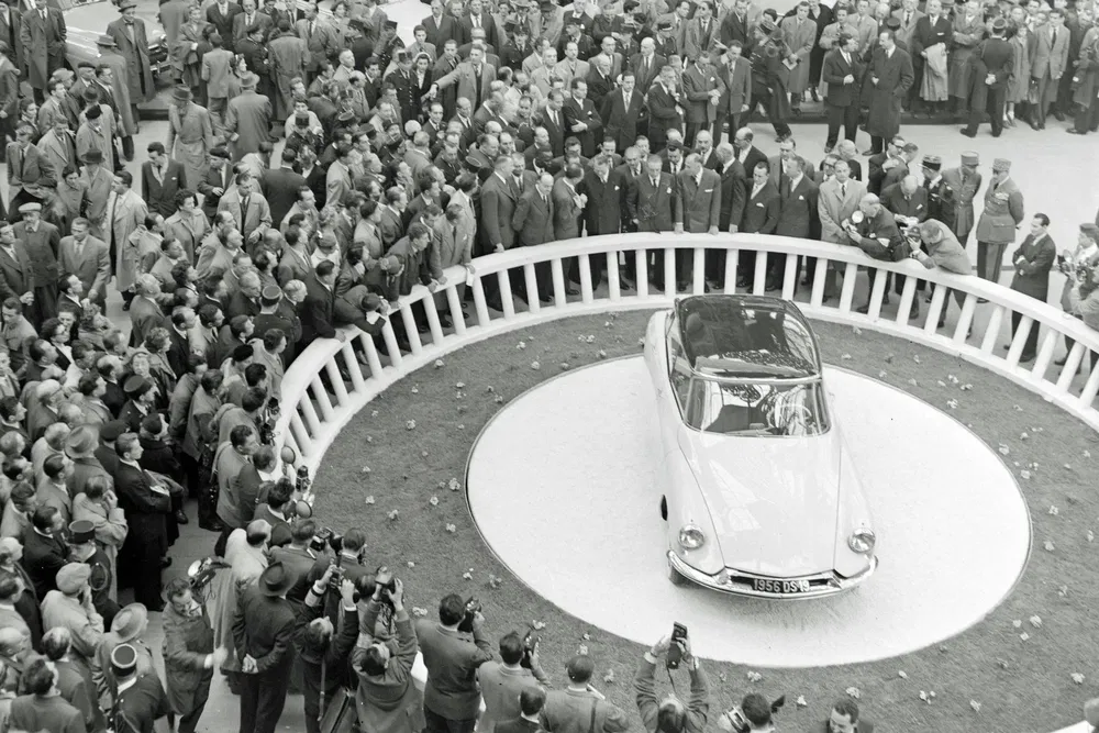 Citroën DS entourée de foule lors d'une exposition automobile historique.