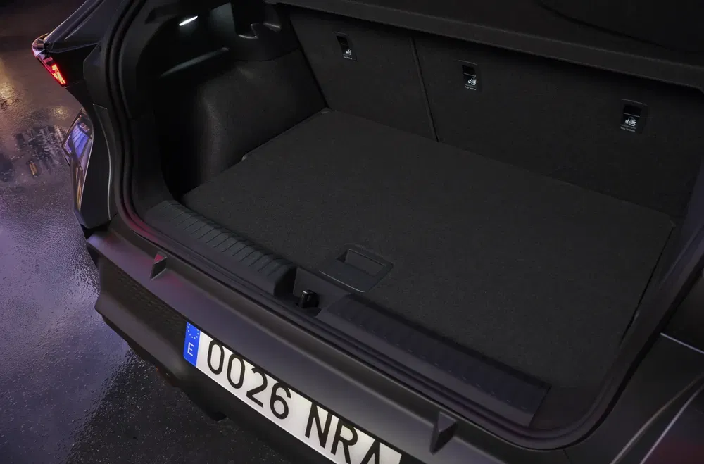 Coffre spacieux d'un SUV moderne avec plaque d'immatriculation espagnole, éclairé dans un garage sombre.