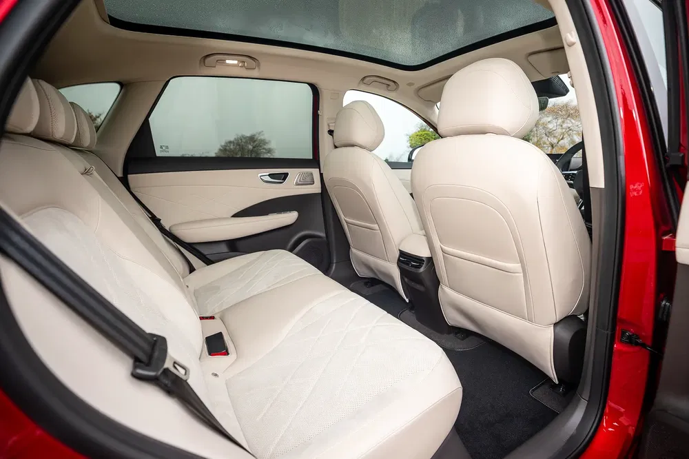 Ruim interieur van een auto met beige leren stoelen en panoramisch dak.