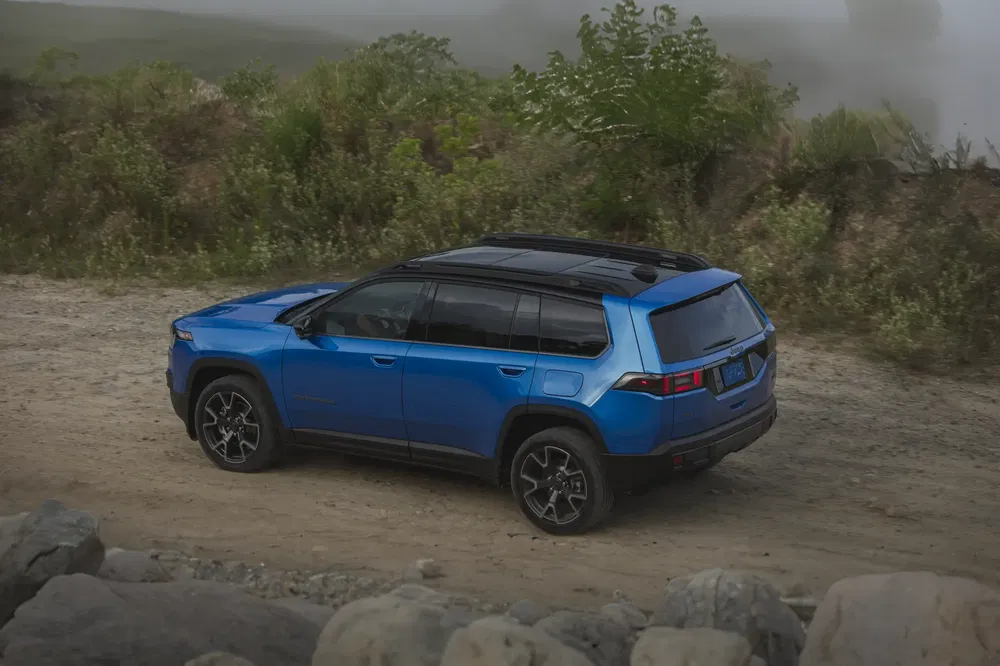 Blauwe Jeep Recon op onverharde weg, klaar voor off-road avontuur.
