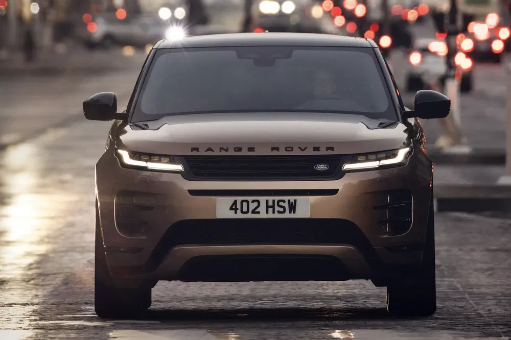 Range Rover sur une route illuminée, phare allumé, plaque d'immatriculation 402 HSW.