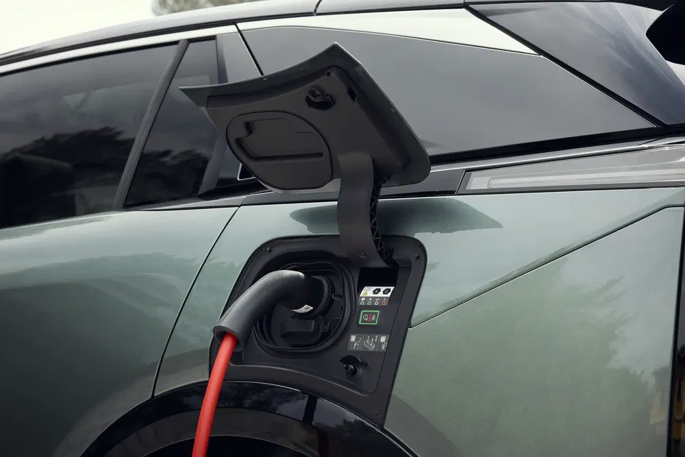 Oplaadkabel aangesloten op moderne groene elektrische auto, detailweergave.