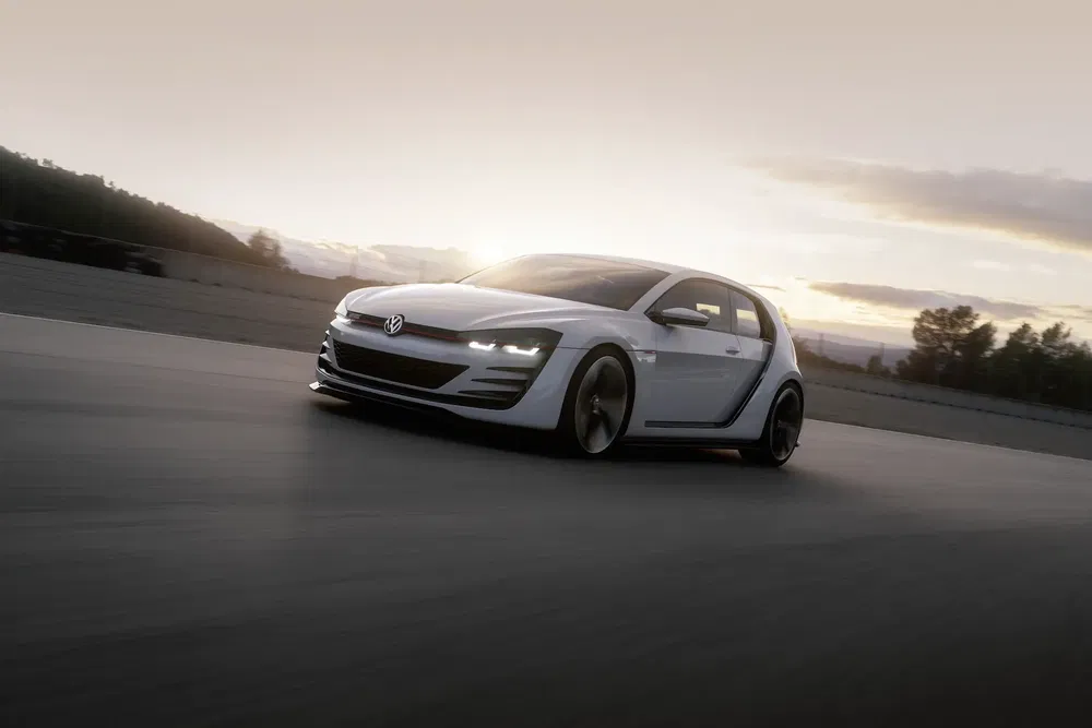 Voiture Volkswagen blanche sur circuit au coucher du soleil, design moderne et aérodynamique.