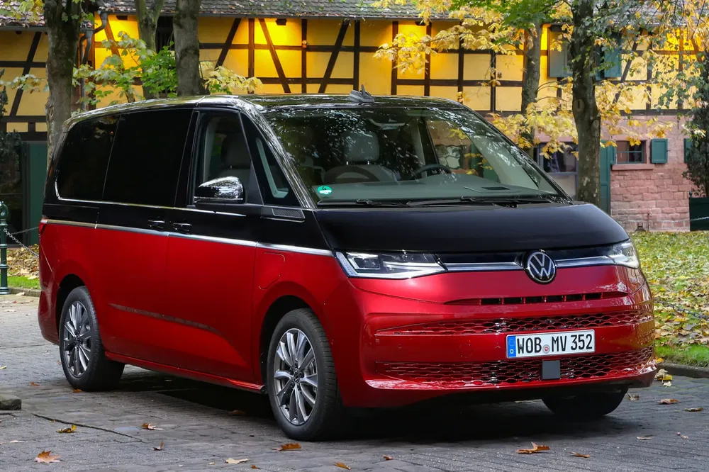 {"fr":"Volkswagen Multivan rouge et noir garé sur une route bordée d'arbres en automne.","nl":"Rode en zwarte Volkswagen Multivan geparkeerd op een met bomen omzoomde weg in de herfst."}