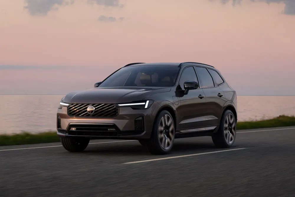 Volvo XC60 2023 sur une route côtière au coucher du soleil.