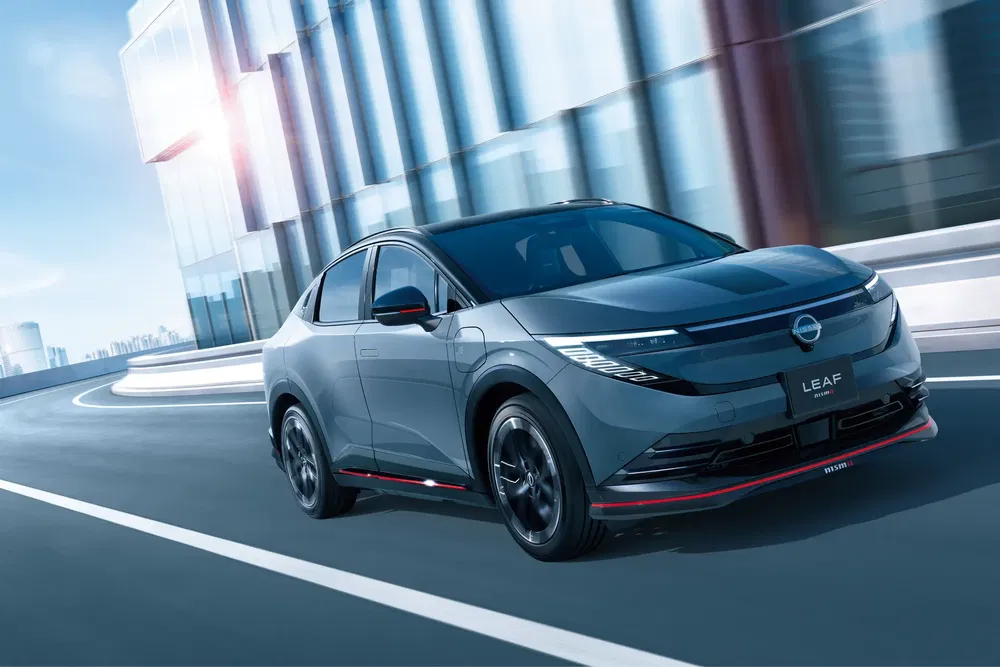 Nissan LEAF noire sur autoroute urbaine moderne, design élégant et aérodynamique.