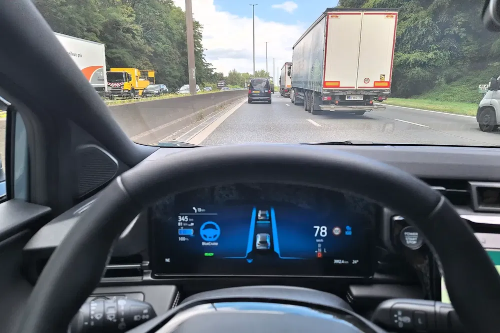 Vue intérieure d'une voiture avec régulateur de vitesse adaptatif sur une autoroute encombrée.