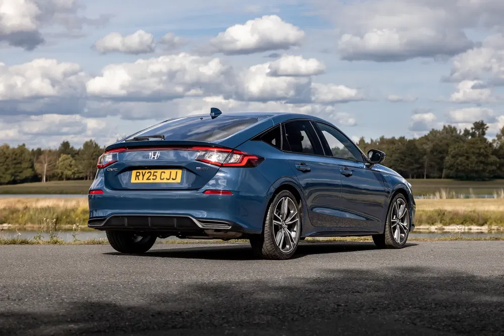 Vue arrière d'une Honda Civic bleue garée sur route avec ciel nuageux.