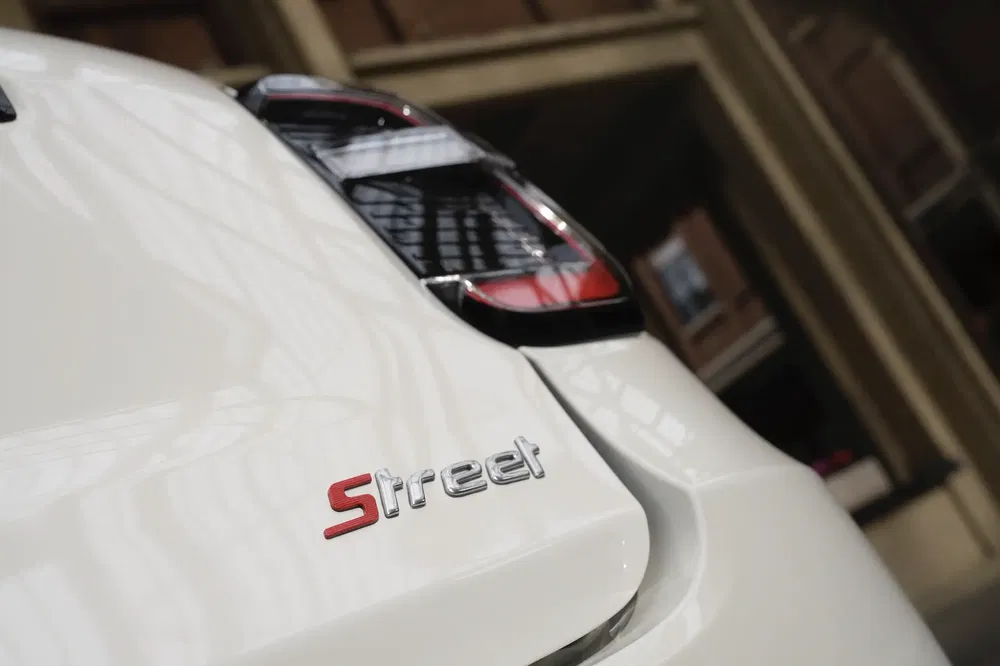 {"fr":"Détail arrière de voiture blanche avec insigne 'Street', feux arrière visibles.","nl":"Achterkant van een witte auto met 'Street'-embleem en zichtbare achterlichten."}