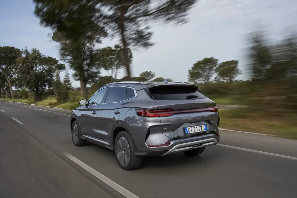 SUV moderne roulant sur une route bordée d'arbres, illustrant une conduite dynamique.