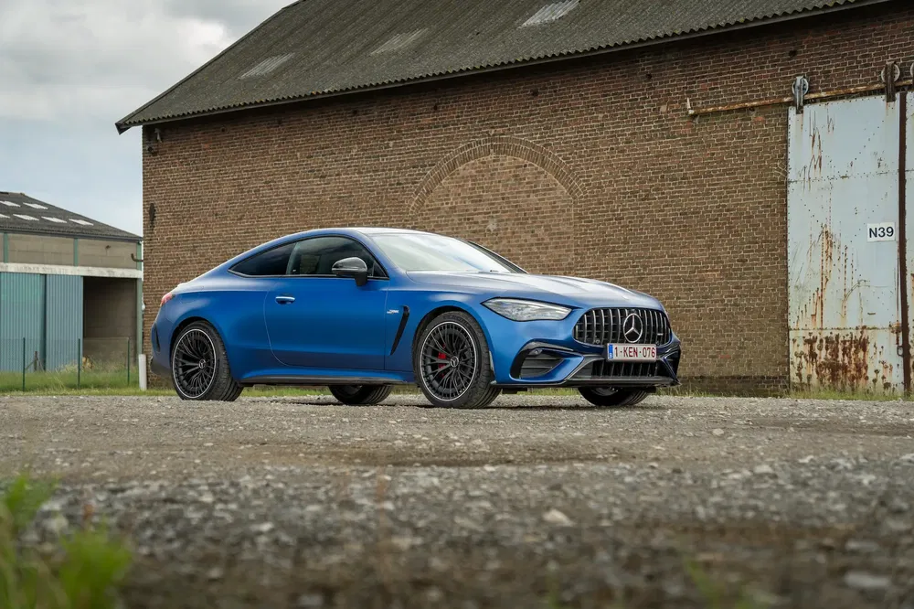 Mercedes-AMG GT Coupé bleu devant un bâtiment en briques, atmosphère industrielle.