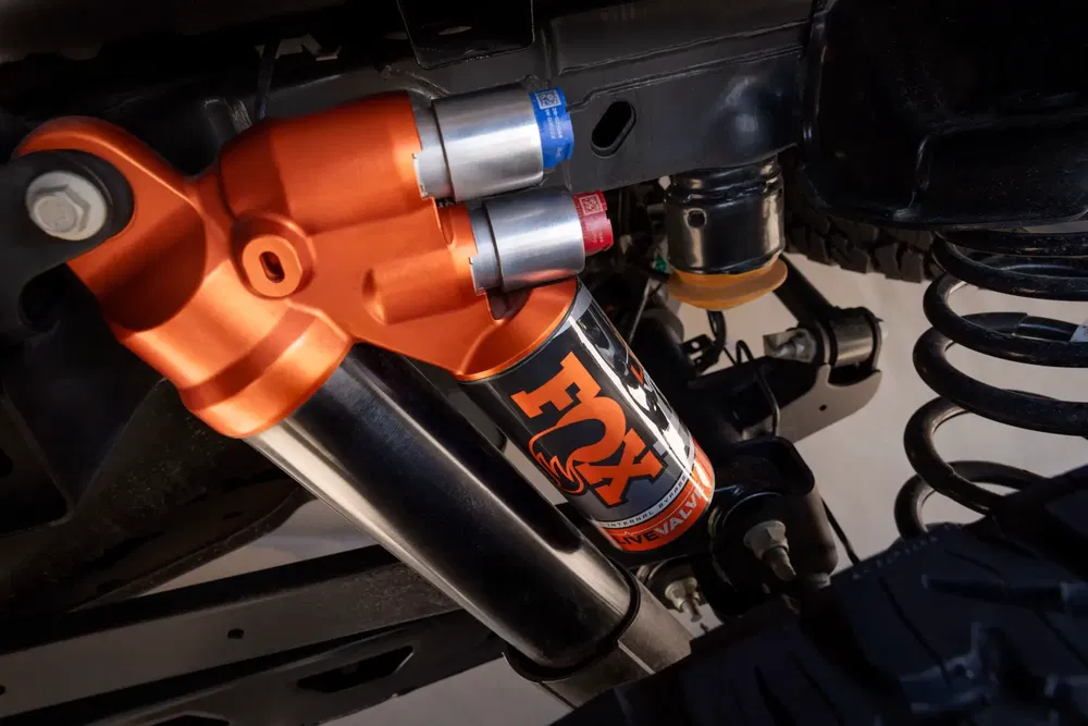 Suspension Fox Racing Shox orange sur châssis de véhicule tout-terrain.