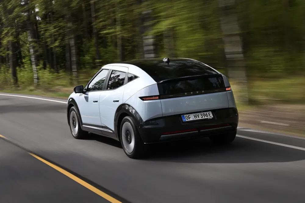 Hyundai Ioniq 5 électrique sur route de campagne bordée d'arbres, design moderne et aérodynamique.