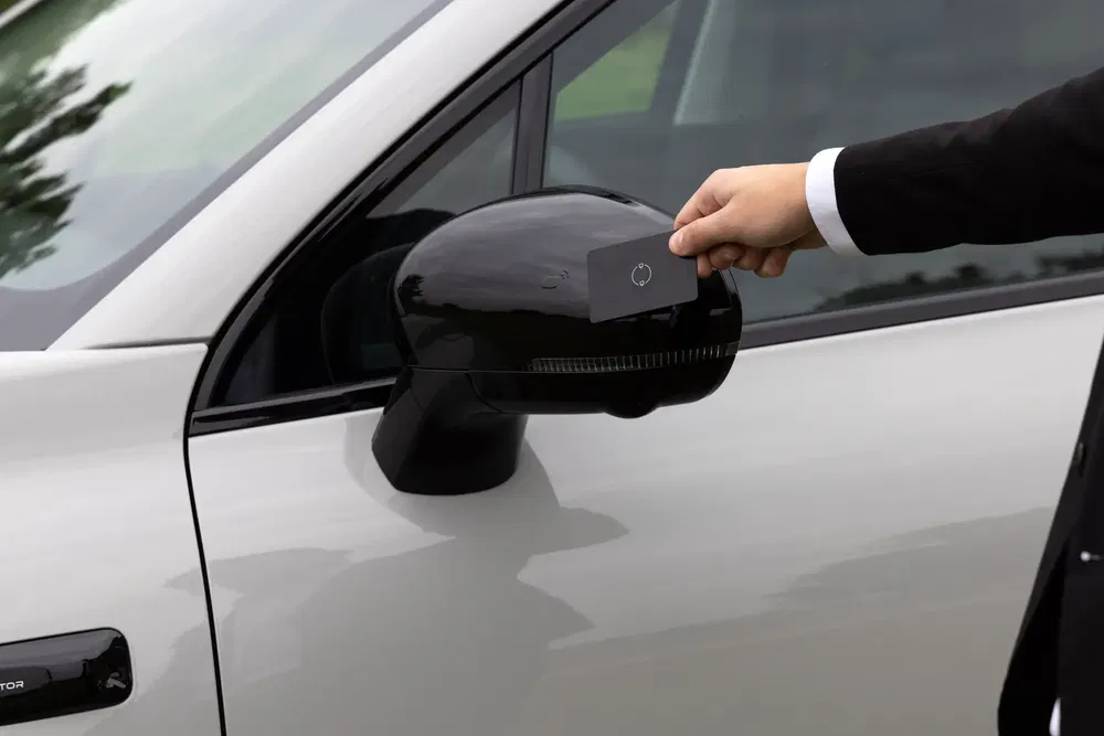 Clé numérique de voiture posée sur le rétroviseur latéral, serrure sans clé moderne.